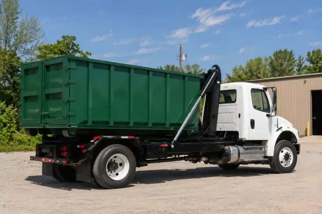 Roll-Off Dumpster Rental in Asheville, NC - Fast, Local & Flat-Rate 4 White roll-off dumpster truck carrying a green 20 yard roll off dumpster container at an industrial yard in Asheville NC for residential and commercial dumpster rental service.