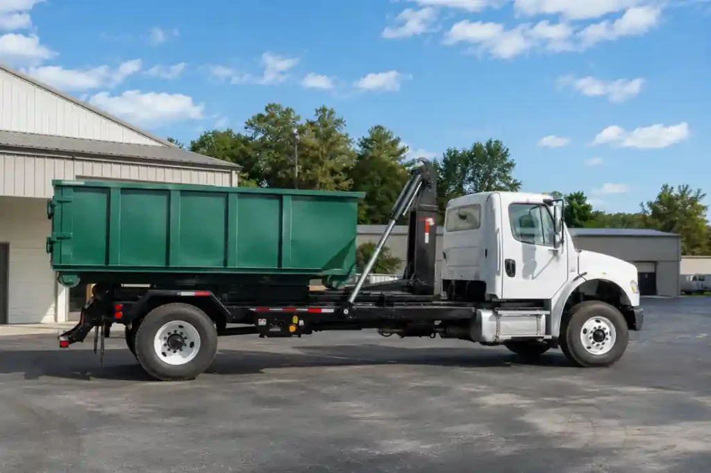Roll-Off Dumpster Rental in Asheville, NC - Fast, Local & Flat-Rate 2 Realistic white roll-off dumpster truck carrying a green 10-yard dumpster container in an outdoor industrial lot with buildings and trees under a bright daytime sky.